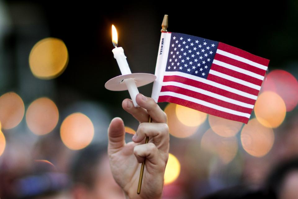 <p>A mourner holds up an American flag and a candle during a vigil, Sunday, June 12, 2016, in Atlanta. (AP/David Goldman) </p>