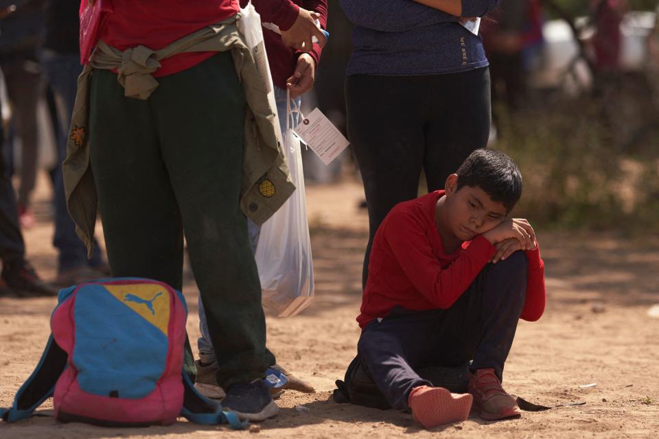 This picture taken on October 9, 2022 shows a young boy sitting on the floor as migrants wait to be processed by US Border Patrol after they illegally crossed the US southern border with Mexico on October 9, 2022 in Eagle Pass, Texas. / Credit: ALLISON DINNER/AFP via Getty Images