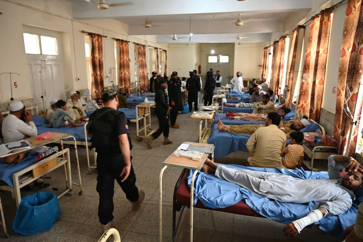 Security personnel walk past bomb blast victims at a hospital (AFP via Getty Images)