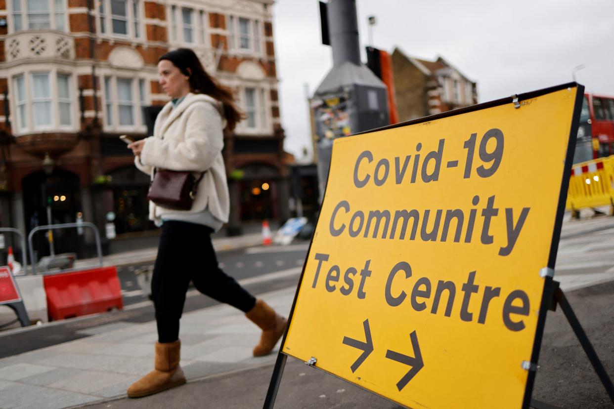 A pedestrian walks past a directional sign for a Covid-19 test centre on Hoe Street in Walthamstow, north London on December 30, 2021. - Fuelled by the highly contagious Omicron variant, daily cases of Covid-19 in England have ballooned, standing at more than 183,000 on Wednesday. (Photo by Tolga Akmen / AFP) (Photo by TOLGA AKMEN/AFP via Getty Images)