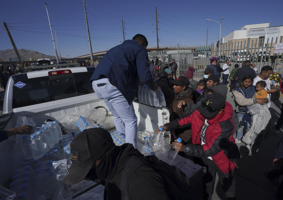 Volunteers hand out water to migrants who are standing outside an immigration detention center where a fire killed dozens, in Ciudad Juarez, Mexico, Tuesday, March 28, 2023. According to Mexican President Andres Manuel Lopez Obrador, migrants fearing deportation set mattresses ablaze at the center, starting the fire. (AP Photo/Fernando Llano)