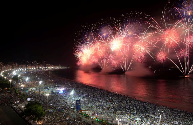 People watch as fireworks explode over Copacabana beach during New Year celebrations in Rio de Janeiro