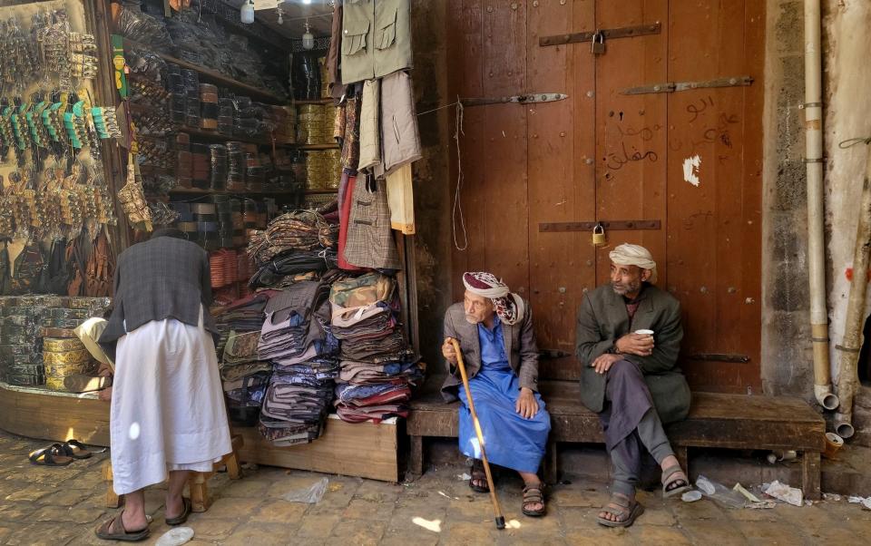 Men sit in front of a shop shop at the old market in Sanaa, Yemen