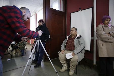 A migrant has his photo taken for an identification card during a workshop for legal advice held by the Familia Latina Unida and Centro Sin Fronteras at Lincoln United Methodist Church in south Chicago, Illinois, January 10, 2016. REUTERS/Joshua Lott