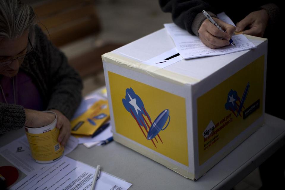 In this photo taken on Sunday, Jan. 12, 2014, a citizen from Barcelona signs a form during a campaign to encourage citizens to exercise their right of petition for the independence of Catalonia in Barcelona, Spain. After years of mass protests by Catalans demanding the right to decide whether they want to break away from Spain and form a new European nation, the wealthy northeastern region’s lawmakers vote to ask permission from Spanish authorities to hold a secession referendum in November. The request eight months ahead of a Scottish independence referendum is certain to be denied by the central government in Madrid but is virtually guaranteed of generating even more separatist fervor. (AP Photo/Emilio Morenatti)