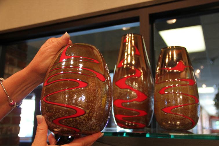 This July 16, 2013 photo shows Lisa Hemm shows vases inspired by the Red River made by artist John Offutt at the Underbrush Gallery in Fargo, N.D. With just over 100,000 people, this city on the eastern edge of the state offers local culture with a good dose of pride and quirkiness. (AP Photo/Coralie Carlson)