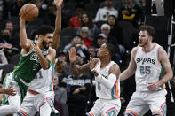 Boston Celtics' Jayson Tatum (0) looks to pass as he is defended by San Antonio Spurs' Dejounte Murray (5), Jakob Poeltl (25), and Keita Bates-Diop during the first half of an NBA basketball game Friday, Nov. 26, 2021, in San Antonio. (AP Photo/Darren Abate)