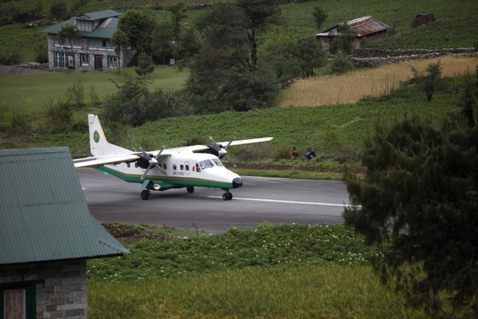 In this Tuesday, May 28, 2013 photo, a plane lands at Lukla airport, Nepal. Carved out of side of a mountain, the airport was built by Sir Edmund Hillary in 1965, and at an altitude of 2,843 meters (9,325 feet) it has earned the reputation of being one of the most extreme and dangerous airports in the world. (AP Photo/Niranjan Shrestha)