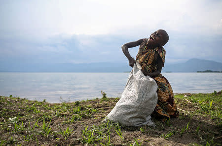 A 10-year-old Pygmy girl laughs as she works weeding the land of a Bahavu farmer on the shore of Lake Kivu on Idjwi island in the Democratic Republic of Congo, November 24, 2016. REUTERS/Therese Di Campo