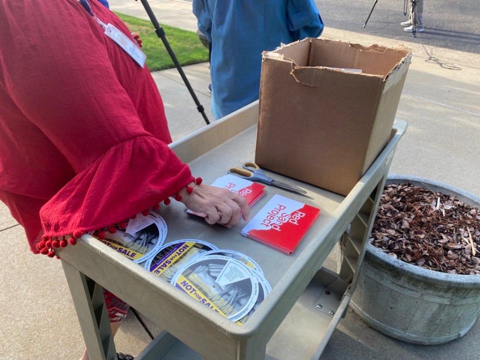 Members of the Jackson-Madison County Regional Health Department gather red sand to pour into the cracks of the department's sidewalks to draw attention to the victims that “fall through the cracks” of society.