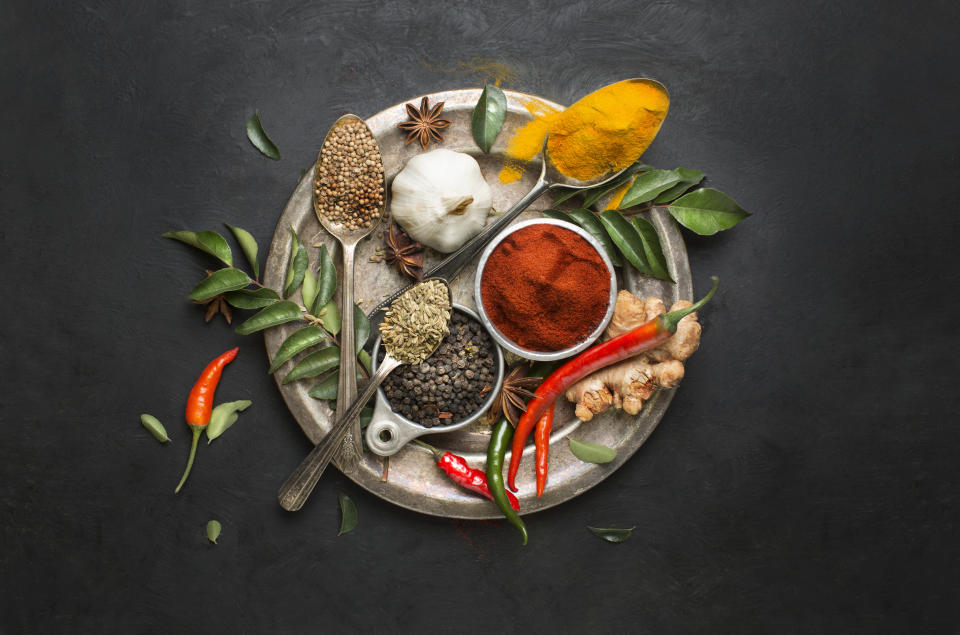 Flat lay overhead view herb and spices in vintage silver plate on textured black background. Asian or indian cuisine colourful spices close up image.