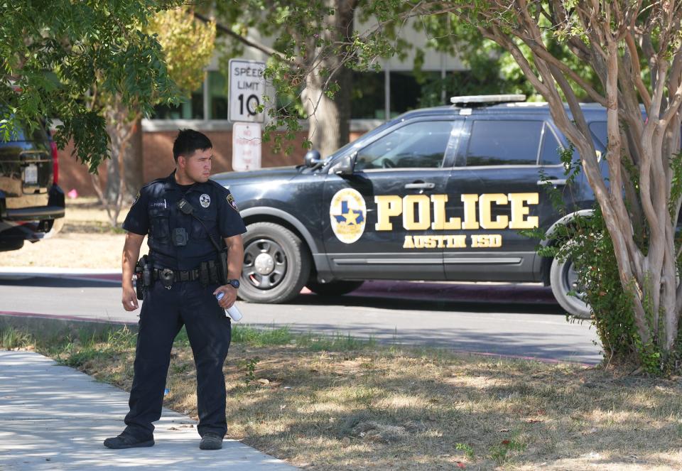 An Austin school police officer stands guard after a body was found on the southwestern side of the Travis High campus in South Austin.