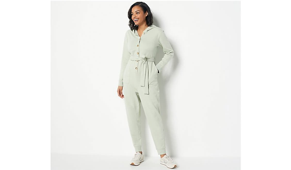 Woman wearing sage one piece with button front and tie belt and sneakers