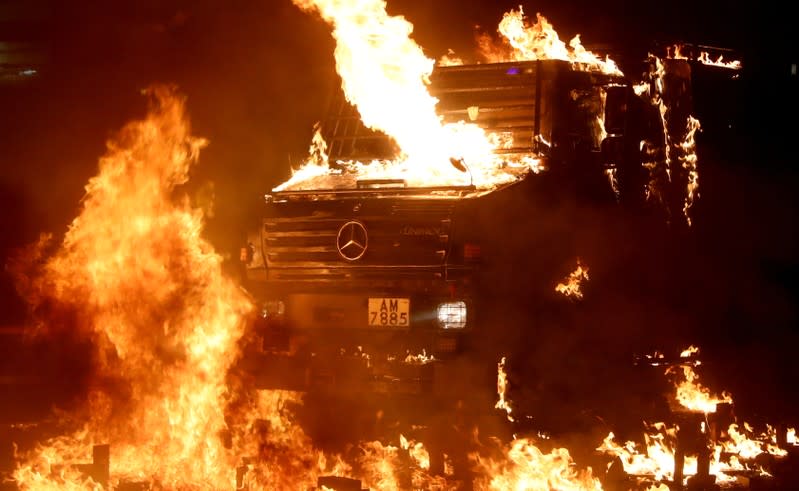 A police vehicle catches fire after being hit with molotov cocktails, as anti-government protesters clash with police, outside Hong Kong Polytechnic University