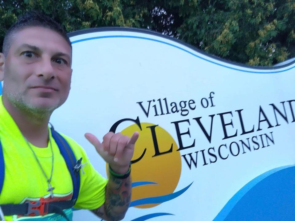 Cudahy resident Greg Studzinski walked away from addiction by walking 136 miles from Green Bay to Cudahy over five days in early September. Here his poses in front of the Village of Cleveland sign.