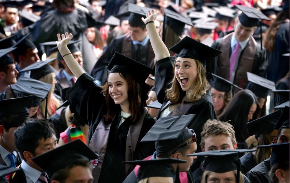 Graduates Noam Bizan and Lauren Jacoby wave to family and friends spotted along the Brown University College Green where commencement was about to take place.