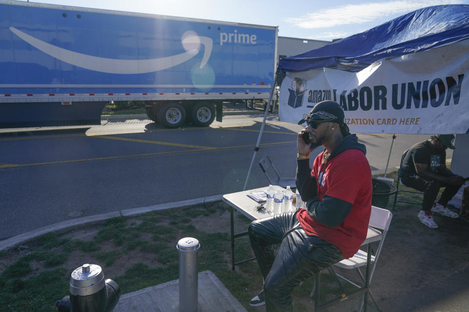 Chris Smalls, president of the Amazon Labor Union, talks on his phone while an Amazon truck passes by in the Staten Island borough of New York, Thursday, Oct. 21, 2021. A bid to unionize Amazon workers at the distribution center in New York City neared an important milestone, as organizers prepared to deliver hundreds of signatures to the National Labor Relations Board as soon as Monday for authorization to hold a vote. (AP Photo/Seth Wenig)