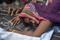 A relative mourns near the body of one of victims of a road accident in Kanpur, Uttar Pradesh state, India, Sunday, Oct.2, 2022. A farm tractor pulling a wagon loaded with people overturned and fell into a pond in Kanpur city's Ghatampur area Saturday night killing 26 people, most of them women and children. (AP Photo)