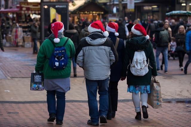 People in Santa hats doing last-minute Christmas shopping