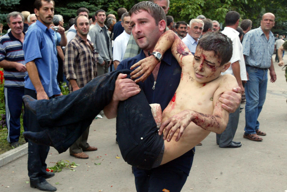 FILE - A wounded boy is carried after he escaped from a seized school in Beslan, Russia, on Sept. 3, 2004. Islamic militants seize a school in the southern city of Beslan, and more than 300 people die in the chaotic explosions and shootout that end the siege two days later. Putin blames regional leaders' incompetence and announces that governors will be appointed figures rather than elected. (AP Photo/Ivan Sekretarev, File)