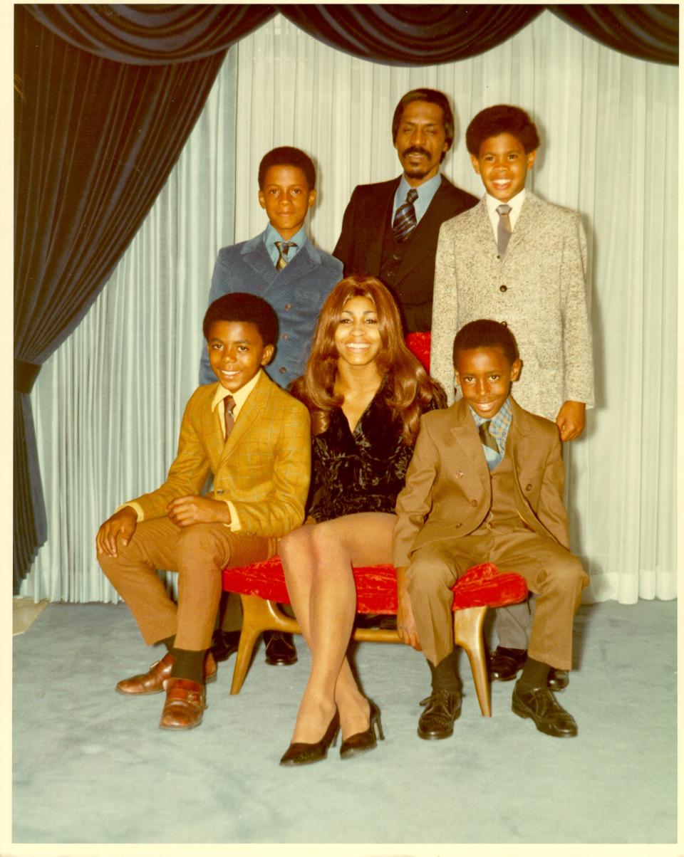 A family photo of the Turners and their sons sitting on a red ottoman.