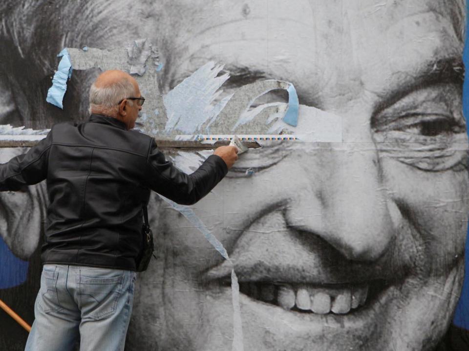 Activists of the Hungarian Együtt (Together) opposition party remove a government billboard displaying George Soros, in Budapest, in October (Reuters)