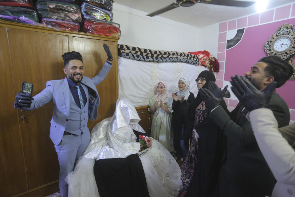 In this Thursday, April 9, 2020 photo, Ahmed Khaled al-Kaabi and his bride Ruqaya Rahim celebrate their wedding in Najaf, Iraq, the hardest hit town by coronavirus in the country with government banned large public gatherings. Unwilling to postpone the wedding, al-Kaabi asked the local security forces to help him wed his beloved. The police responded by providing the groom vehicles blasting music to bring his bride to the family home for a small celebration of just six people. (AP Photo/Anmar Khalil)
