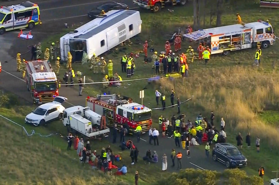 In this image made from video, rescue workers help children from a school bus that rolled onto its side on the outskirts of Melbourne, Australia, Tuesday, May 16, 2023. Seven children remain hospitalized Wednesday, May 17, with serious injuries after a truck struck a school bus Tuesday carrying as many as 45 students in southeastern Australia. (AuBC/CHANNEL 7/CHANNEL 9 via AP)