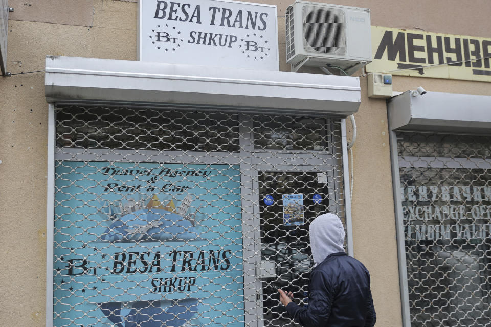 A man stands in front of a closed travel agency Besa Trans in Skopje, Northern Macedonia, Tuesday, Nov. 23, 2021. A bus carrying tourists back to North Macedonia crashed and caught fire in western Bulgaria early Tuesday, killing at least 45 people, including a dozen children, authorities said. (AP Photo/Visar Kryeziu)