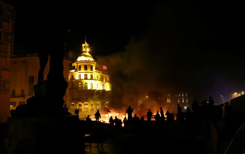 Protesters stand near burning tents during anti government protests in Beirut