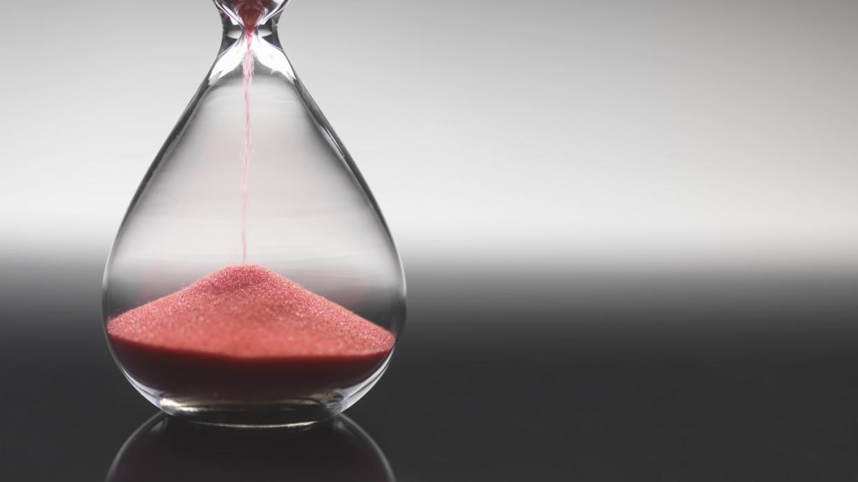 pink sand pouring through hourglass