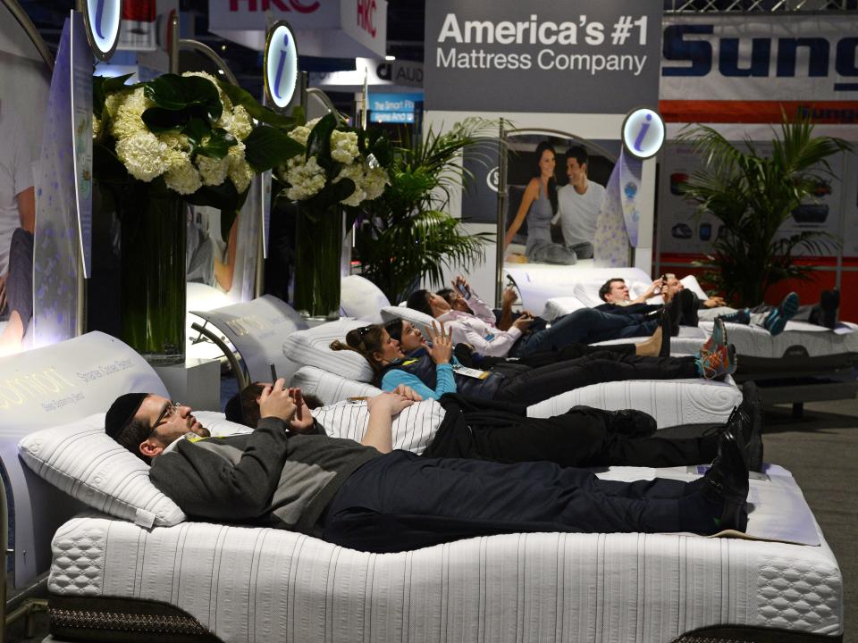 Attendees lay on Serta mattresses at the Serta stand at CES in 2015.