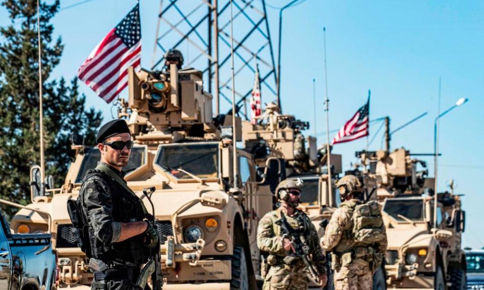 A member of the Kurdish People’s Protection Units (YPG) stands guard as US military armoured vehicles and soldiers patrol near an oil well in Syria’s northeastern Hasakeh province.