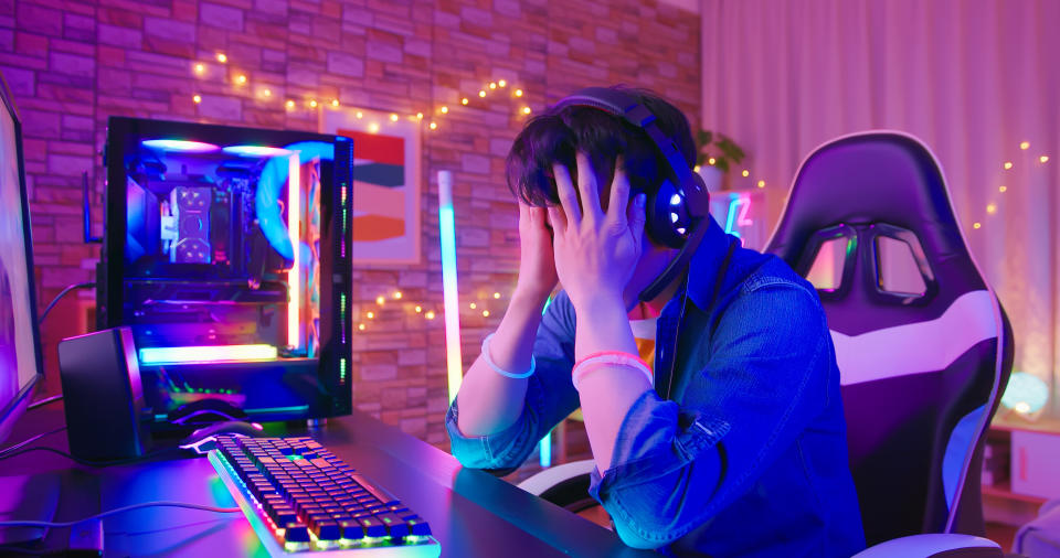 A man with his head in his hands at his computer.