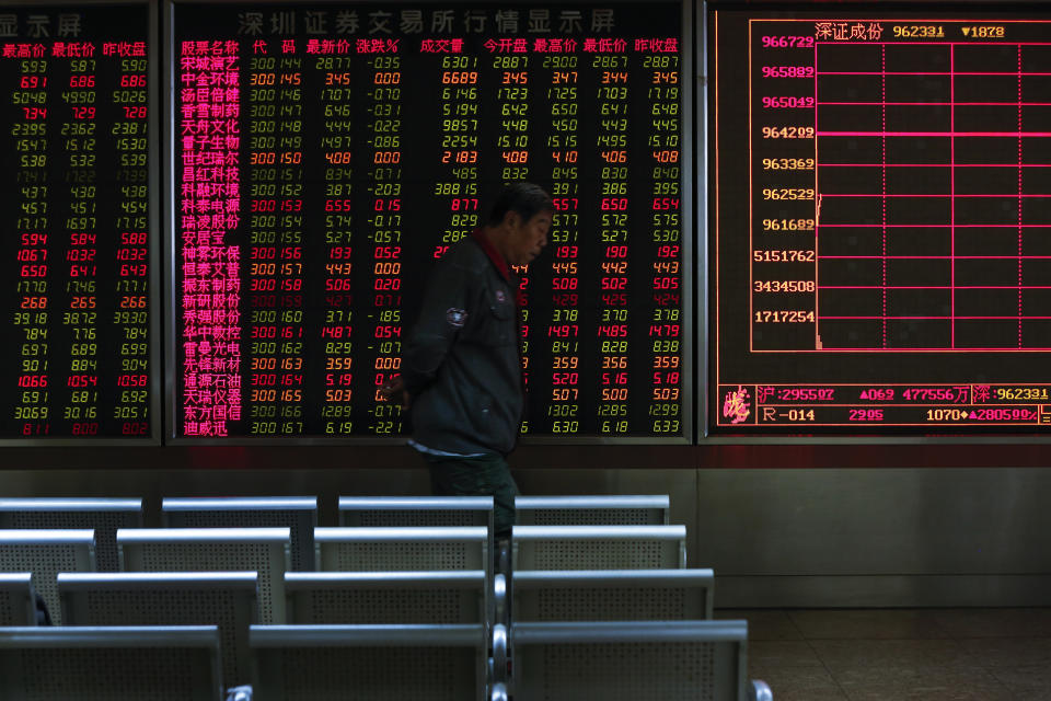 An investor walks by an electronic screen displaying stock prices at a brokerage house in Beijing, Wednesday, Oct. 23, 2019. Asian stock markets followed Wall Street lower Wednesday after major companies reported mixed earnings and an EU leader said he would recommend the trade bloc allow Britain to delay its departure. (AP Photo/Andy Wong)