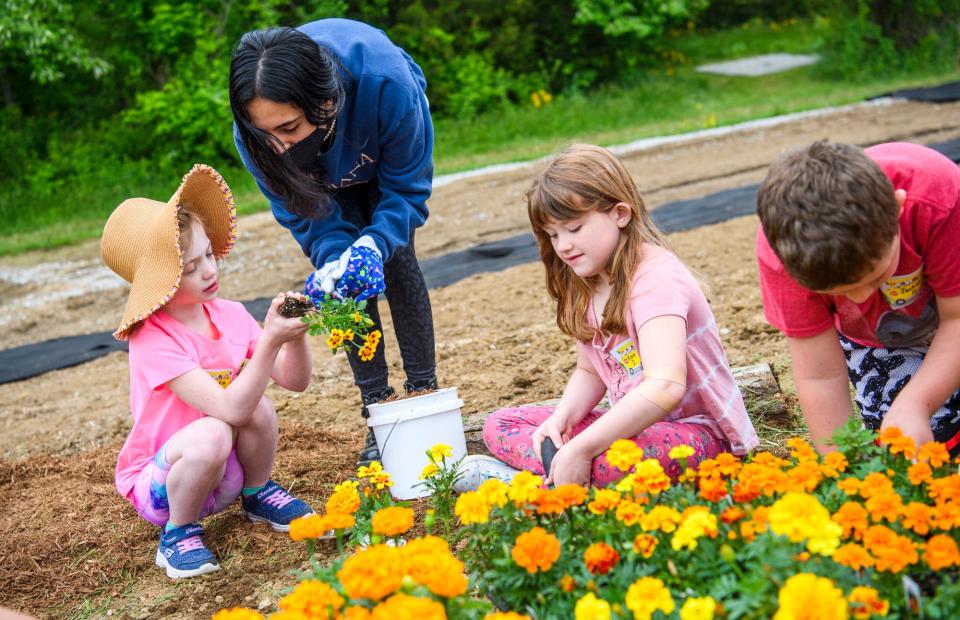 Grandview Elementary student Maddie Wible is helped by Mary Jallal, a volunteer with Ivy Tech Community College, as they plant flowers at the college's Biology Outdoor Learning Lab on Tuesday, May 10, 2022.