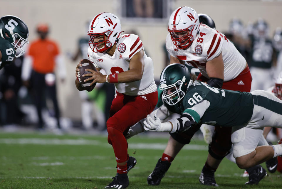 Nebraska quarterback Adrian Martinez (2) escapes from Michigan State's Jacub Panasiuk (96) and Jacob Slade, left, during the second quarter of an NCAA college football game, Saturday, Sept. 25, 2021, in East Lansing, Mich. (AP Photo/Al Goldis)