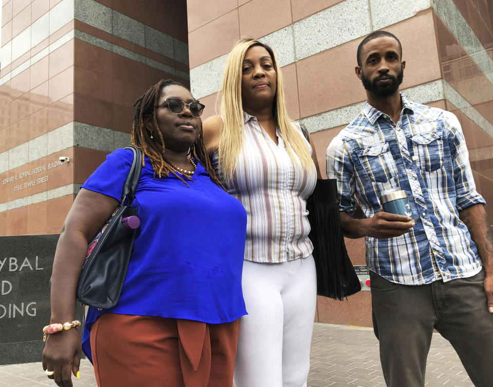 In this Sept. 26, 2019 photo, LaTisha Nixon, center, mother of Gemmel Moore, one of the men who died in the apartment of Democratic donor Edward Buck, poses for a photo with Gemmel's friend Cory McLean, holding a container with Gemmel's ashes, and attorney Nana Gyamfi in downtown Los Angeles. It took more than two years from the first overdose death in political donor Ed Buck's apartment until his arrest this month. In the time in between, another man died in the West Hollywood home, another had a close brush with death and several others reporting harrowing encounters with the gay white man who preyed on young black men to satisfy a drug-fueled sexual fetish. Activists who pushed for Buck's arrest wonder why it took so long to lock him up. (AP Photo/Brian Melley)