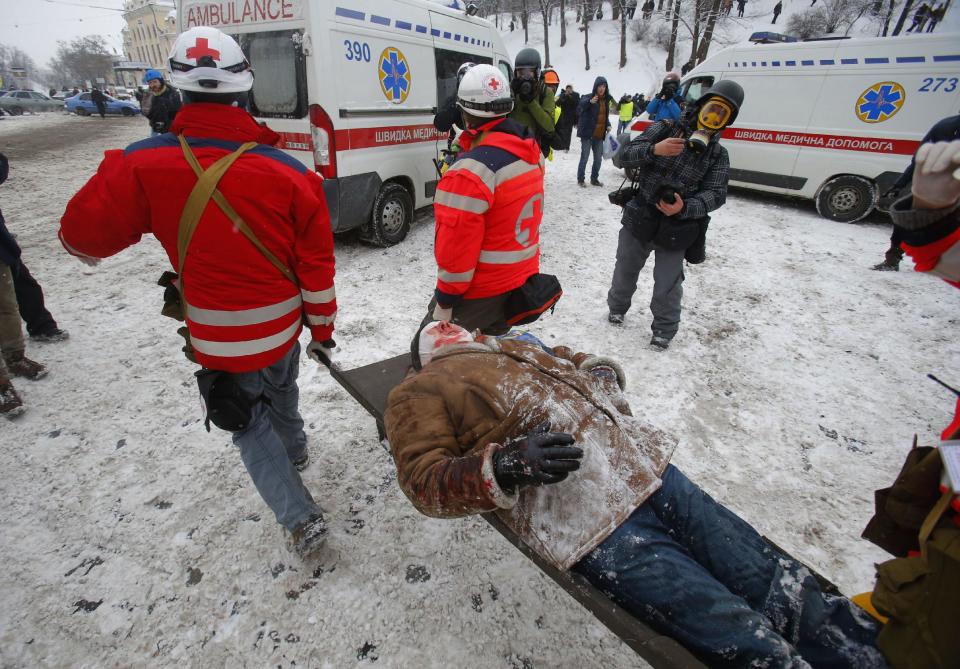 Paramedics carry a wounded protestor on a stretcher away from clashes with police in central Kiev, Ukraine, Wednesday, Jan. 22, 2014. Police in Ukraine's capital on Wednesday tore down protester barricades and chased demonstrators away from the site of violent clashes, hours after two protesters died after being shot, the first violent deaths in protests that are likely to drastically escalate the political crisis that has gripped Ukraine since late November. (AP Photo/Sergei Grits)