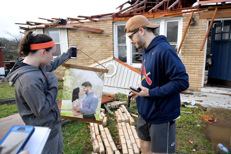 Meg Selby and Mac Warren look over their engagement photo that they found in their damaged house in Stanford Estates after a tornado touched down in Nashville