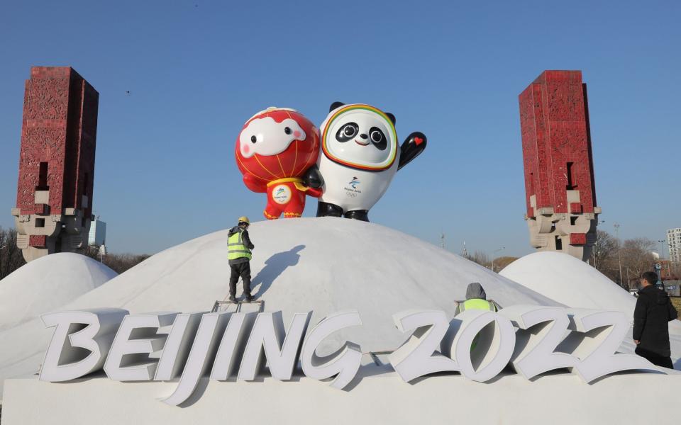 Chinese workers spray paint near the Bing Dwen Dwen, the Beijing 2022 Winter Olympic Mascot and Shuey Rhon Rhon, the 2022 Beijing Winter Paralympic Games Mascot, in Beijing, China, 11 January 2022 - Shutterstock