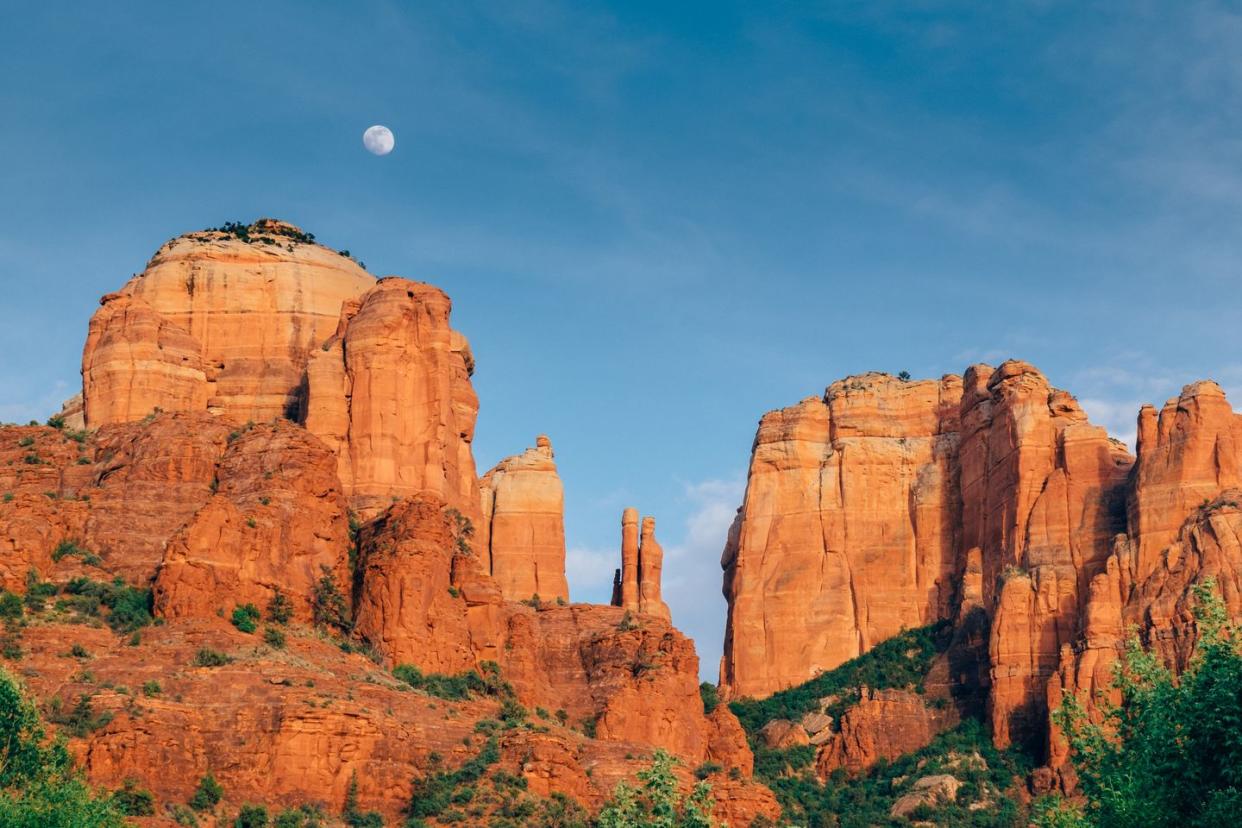 a full moon rises above cathedral rock in sedona