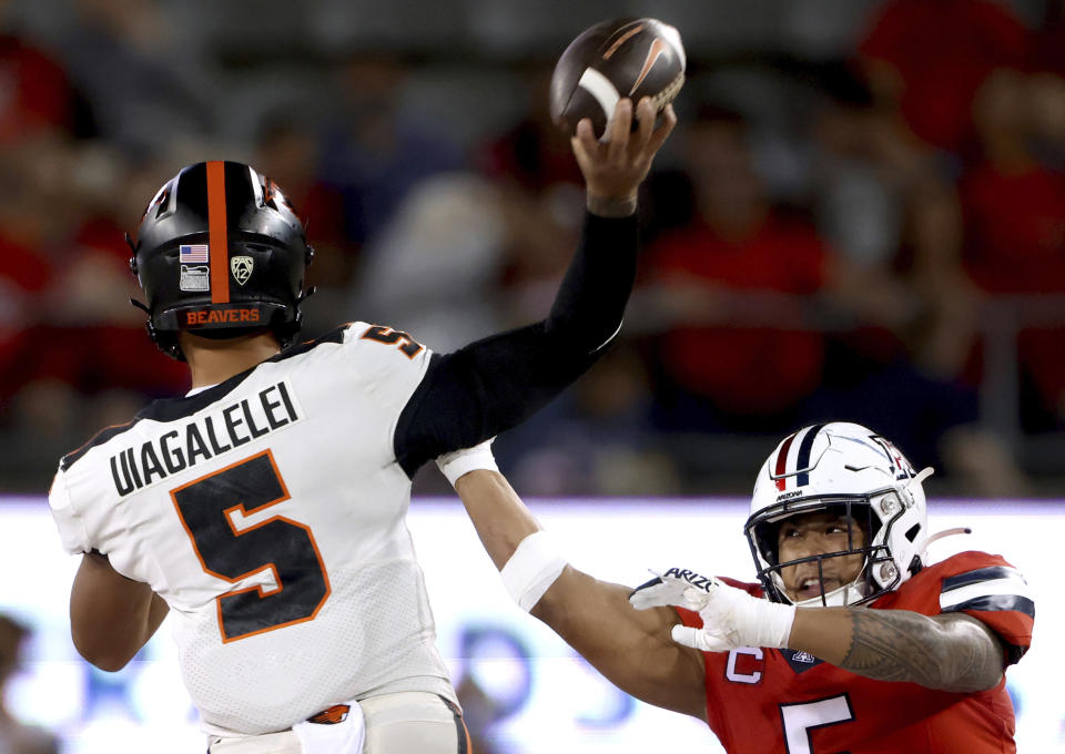 Arizona linebacker Jacob Manu (5) gets a piece of Oregon State quarterback DJ Uiagalelei (5), who threw an incomplete pass during the second quarter of an NCAA college football game Saturday, Oct. 28, 2023, in Tucson, Ariz. (Kelly Presnell/Arizona Daily Star via AP)