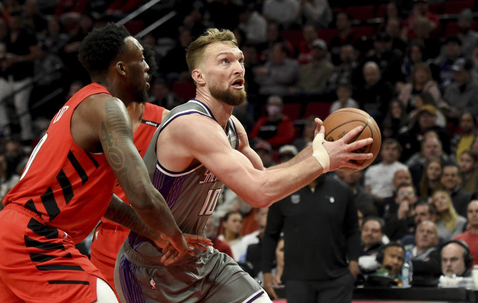 Sacramento Kings forward Domantas Sabonis, right, drives to the basket on Portland Trail Blazers forward Nassir Little, left, during the first half of an NBA basketball game in Portland, Ore., Wednesday, March 29, 2023. (AP Photo/Steve Dykes)