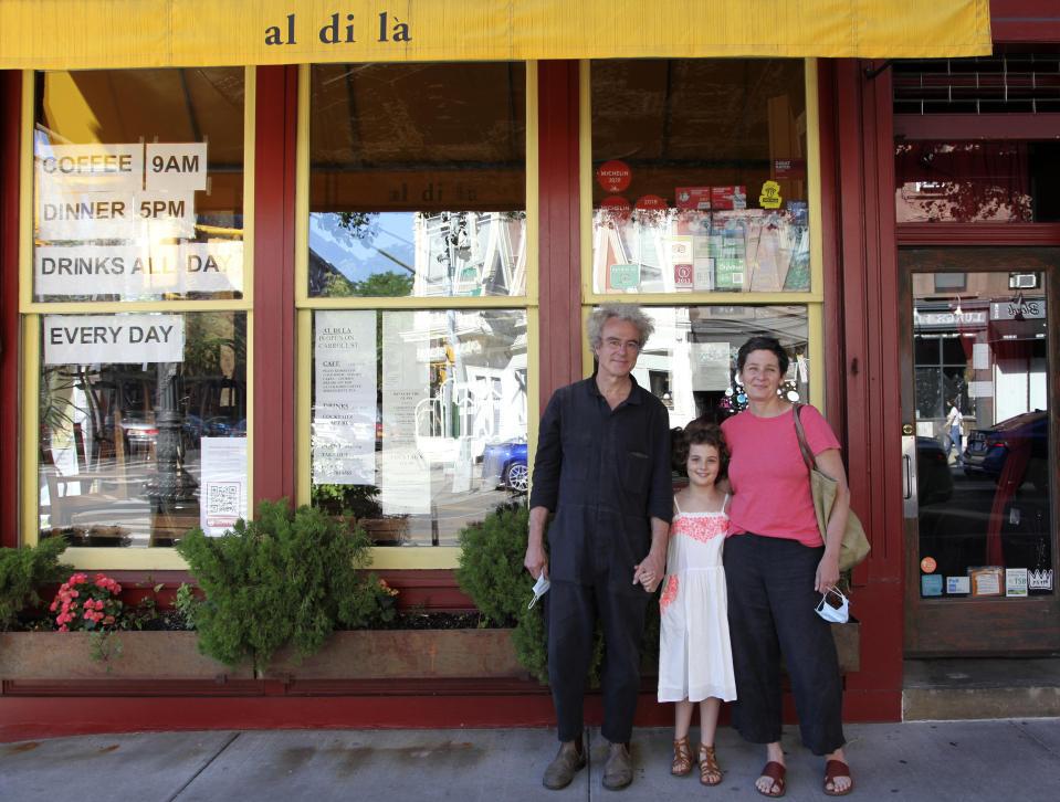 In this June 14, 2020 photo, Emiliano Coppa, left, and chef Anna Klinger pose with their daughter outside their trattoria, Al di La, in the Park Slope neighborhood in the Brooklyn borough of New York. The coronavirus has decimated the restaurant industry, leaving millions unemployed and shuttering spots for good. Many dine-in restaurants have turned to delivery or takeout, like Al di La. (Lisa Tolin via AP)