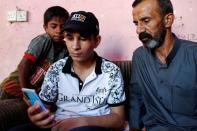 Iraqi teenager Hamid Saeed watches a video with his relatives that circulated on social media of him being mistreated by members of security forces, after being released from jail during an interview with Reuters at his home in Baghdad