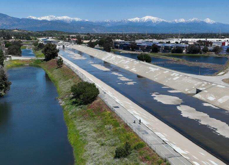 Pico Rivera, CA - April 04: On a sunny, windy and clear day, people skateboard on the Rio Hondo Bike Path with a view of snow-capped San Gabriel mountains and lots of water filtering in the nearby Rio Hondo River Coastal Basin Spreading Grounds in Pico Rivera after recent storms Tuesday, April 4, 2023. The Rio Hondo Coastal Basin Spreading Grounds is Los Angeles County Public Works' largest spreading facility, cover about 570 acres. Water is diverted from the Rio Hondo Channel and the San Gabriel River to replenish the ground water aquifer. (Allen J. Schaben / Los Angeles Times)