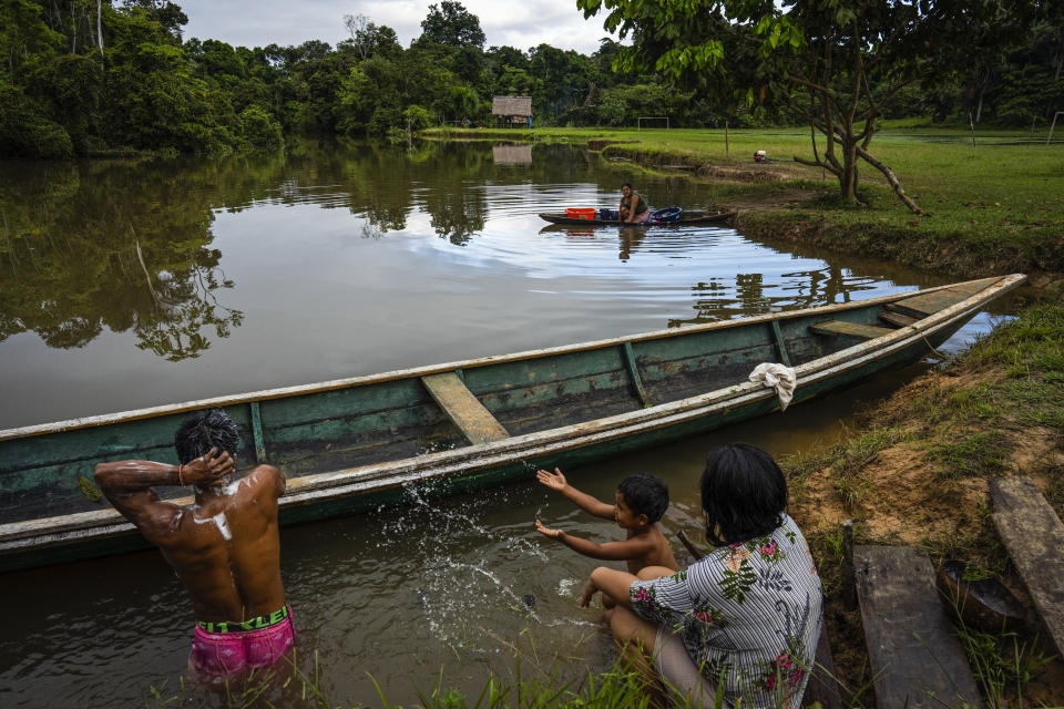 Maijuna youth Miguel splashes water toward his father Teodoro Flores who bathes in a stream in Sucusari, Peru, Wednesday, May 29, 2024. A federal highway project in an untouched area of the Peruvian Amazon is facing mounting opposition from Indigenous tribes, including the Maijuna. (AP Photo/Rodrigo Abd)