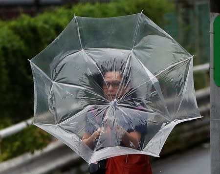 A woman using an umbrella struggles against a heavy rain and wind caused by Typhoon Faxai in Tokyo