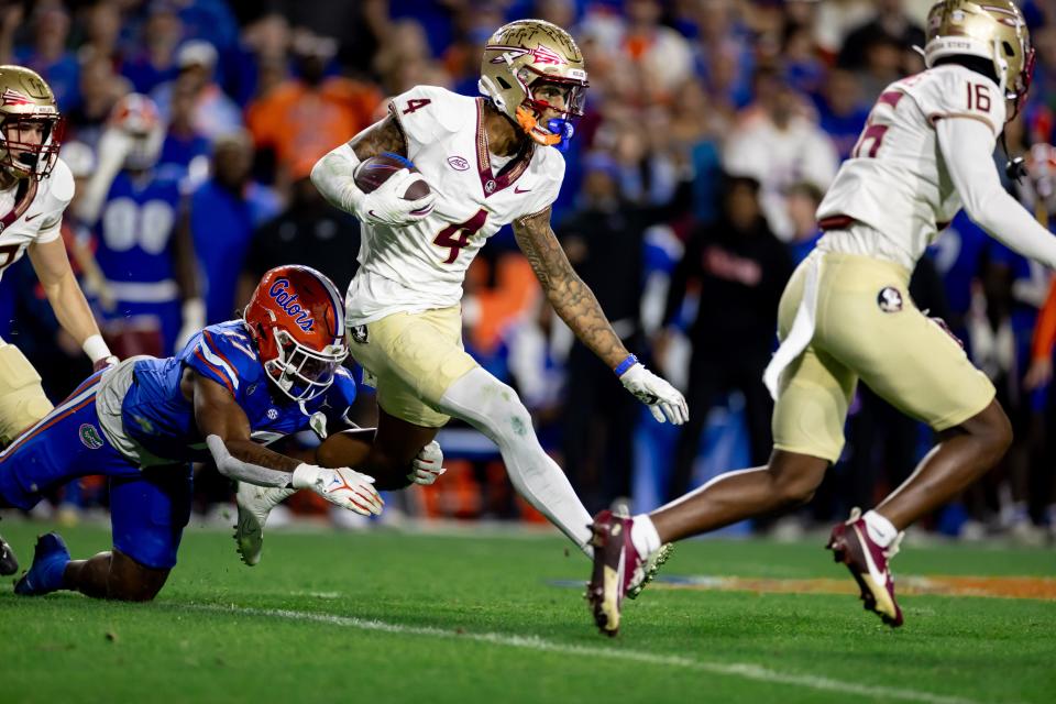 Florida State Seminoles wide receiver Keon Coleman (4) rushes with the ball for a touchdown breaking the tackle from Florida Gators linebacker Scooby Williams (17) during the second half at Steve Spurrier Field at Ben Hill Griffin Stadium in Gainesville, FL on Saturday, November 25, 2023. [Matt Pendleton/Gainesville Sun]